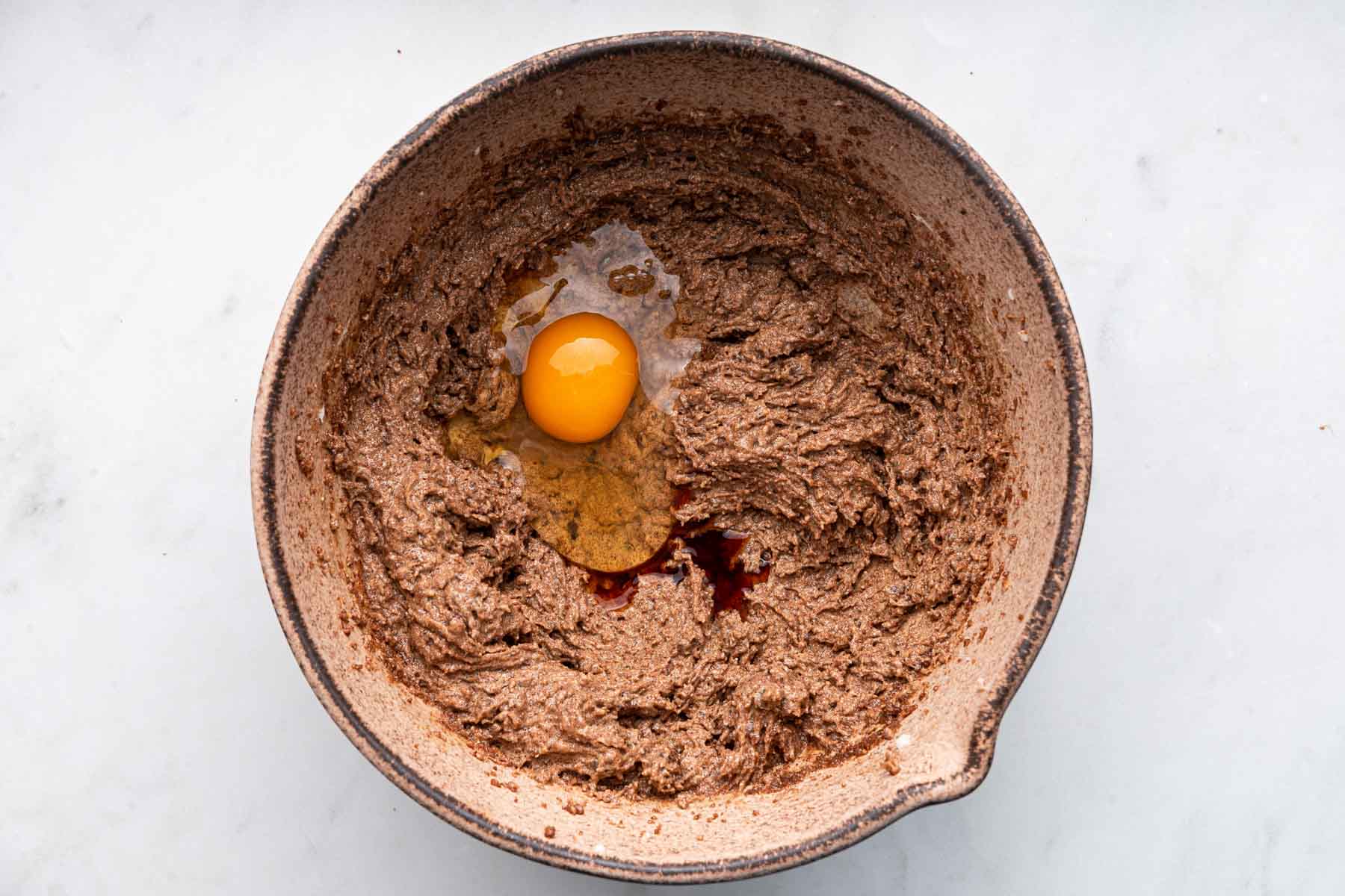 Brown dough with raw egg and splash of vanilla on top.