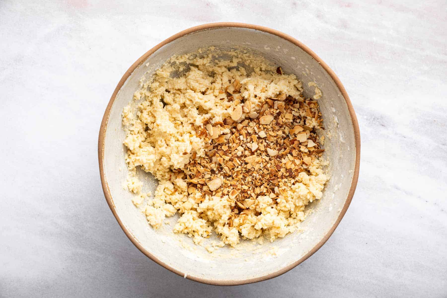 Pale yellow dough with toasted sliced nuts on top.
