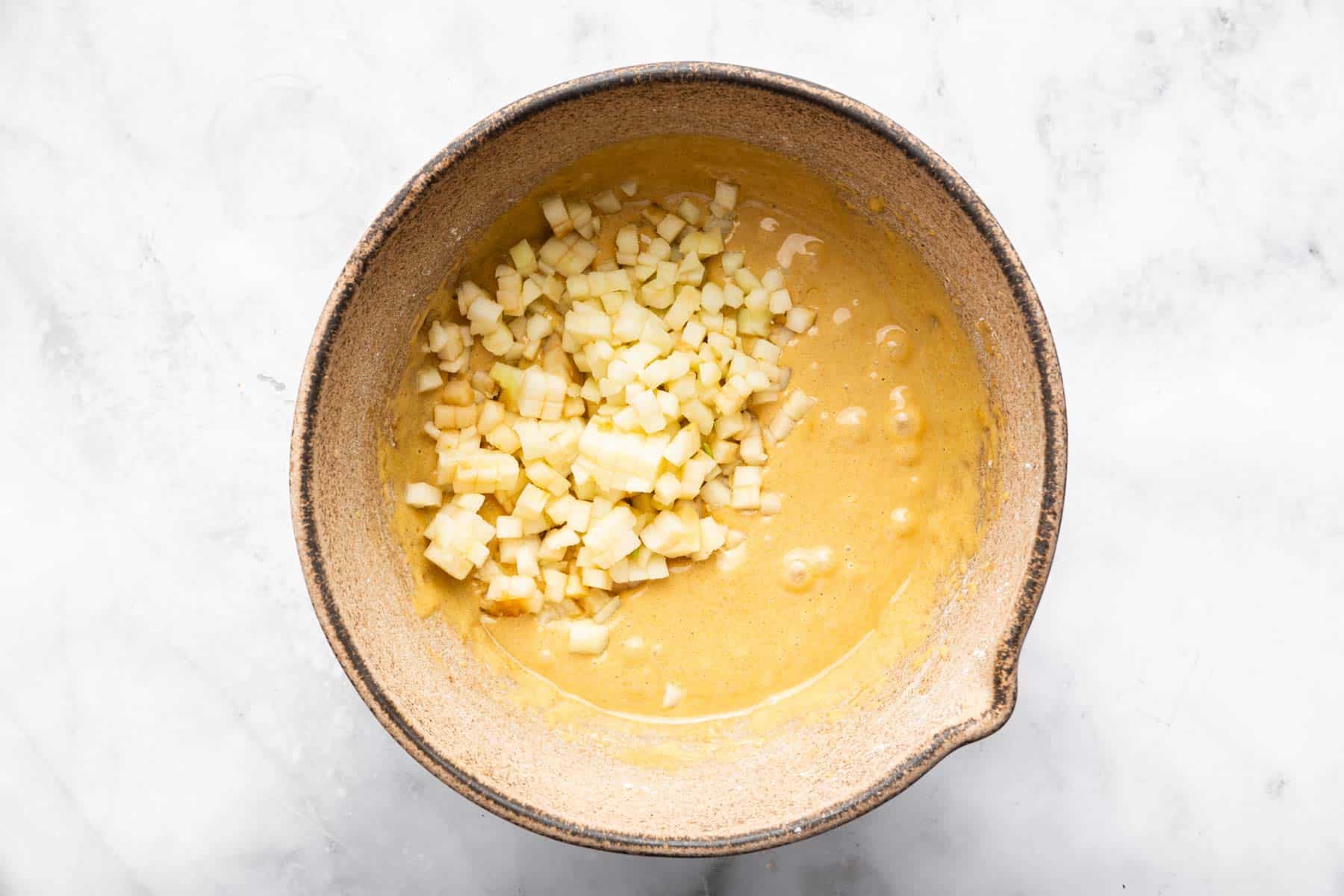 Yellow batter with finely chopped apples on top.