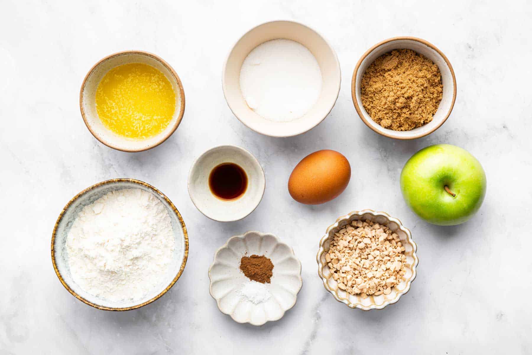 Bowls of melted butter, brown sugar, fruit, toffee bits, and spices.