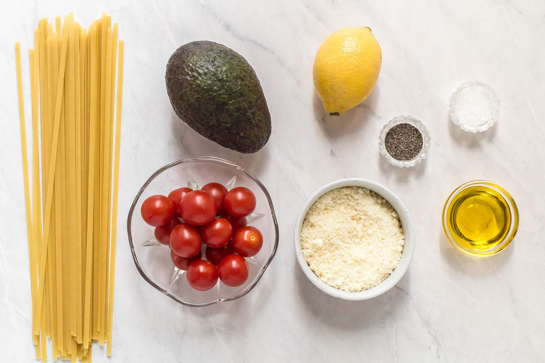 Ingredients for avocado pasta sauce on white table.
