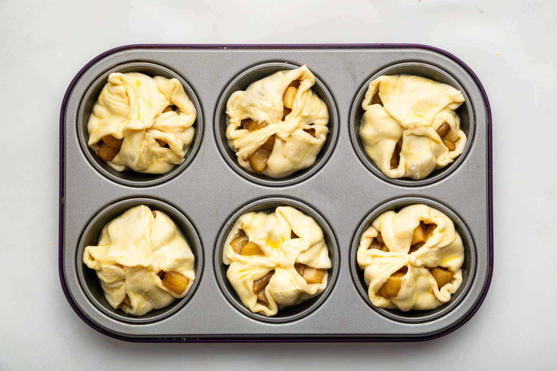 Muffin pan with raw pastry cups before being baked.