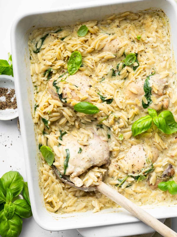 Baked Chicken Orzo with spinach and creamy cheese garnished with basil.