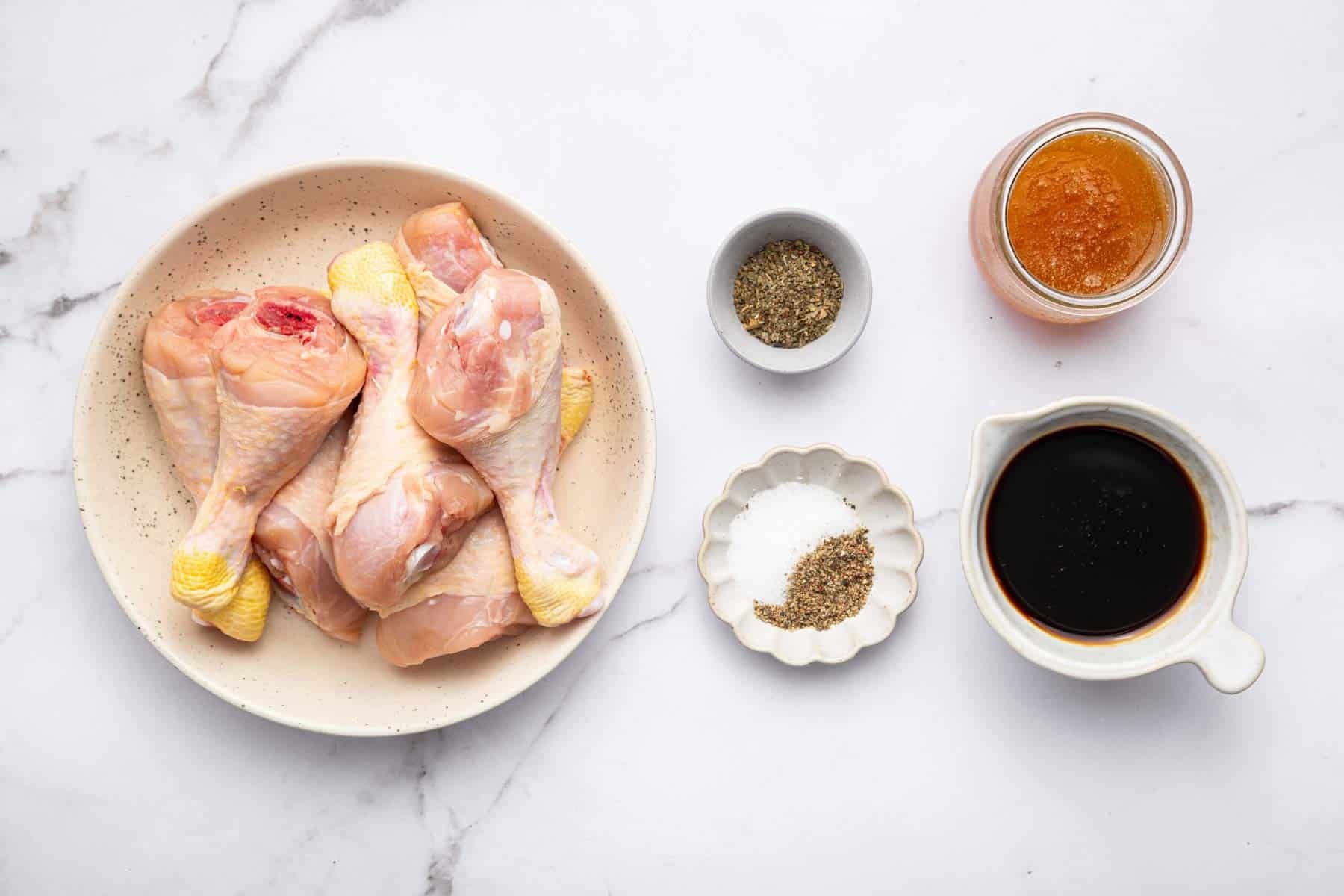 Plate of drumsticks, spices, brown liquid and honey.