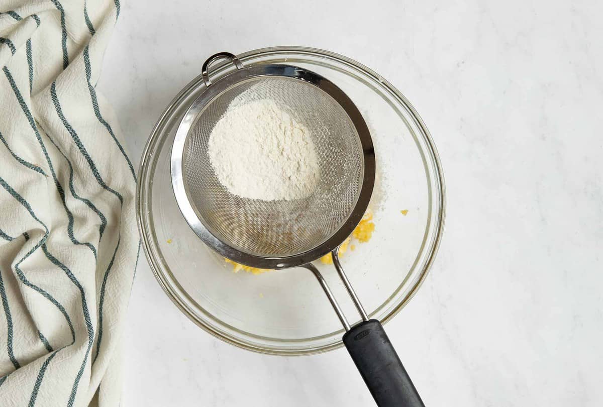 Flour sifting into bowl with dough.
