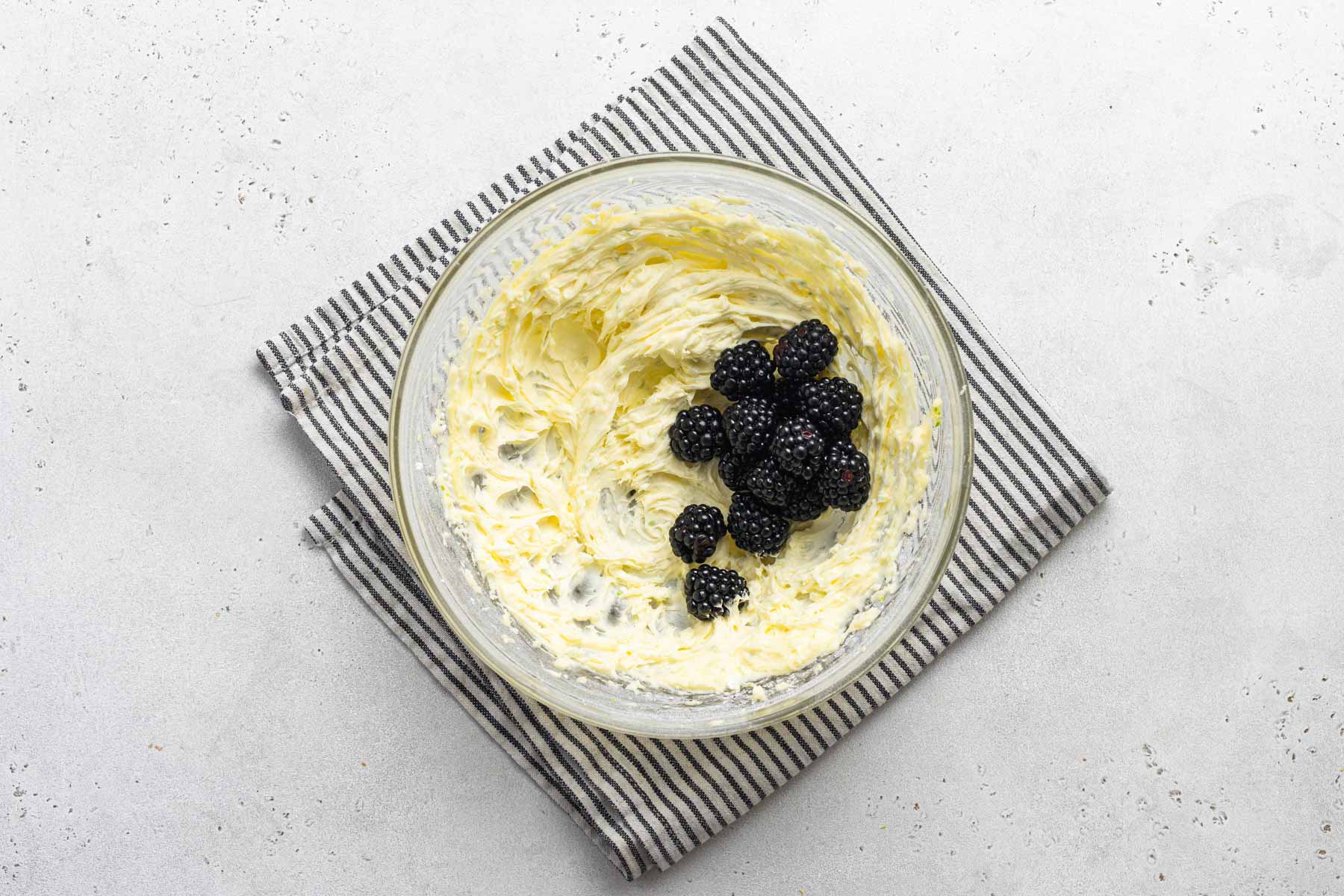 Fresh blackberries going into buttercream frosting.