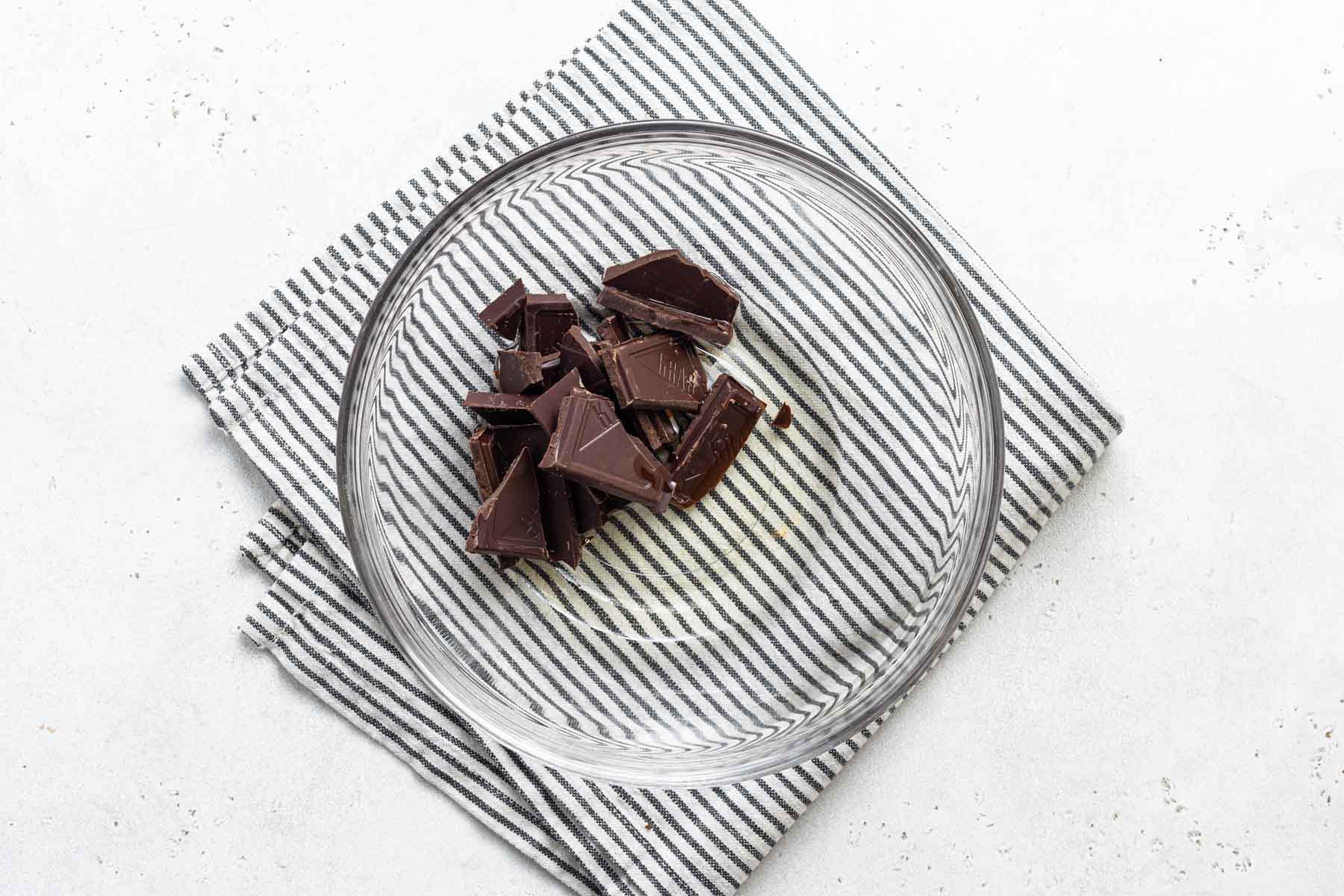 Chopped chocolate and oil in glass bowl.