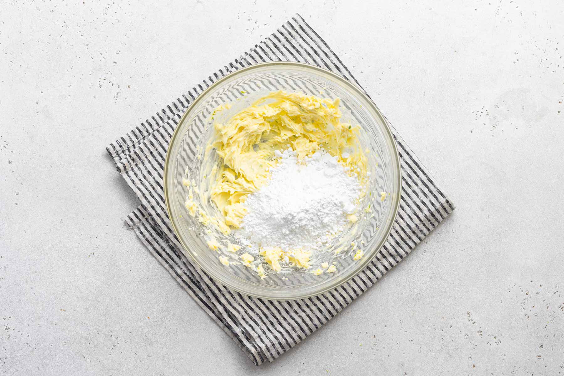 Powdered sugar in bowl with butter and lime zest.