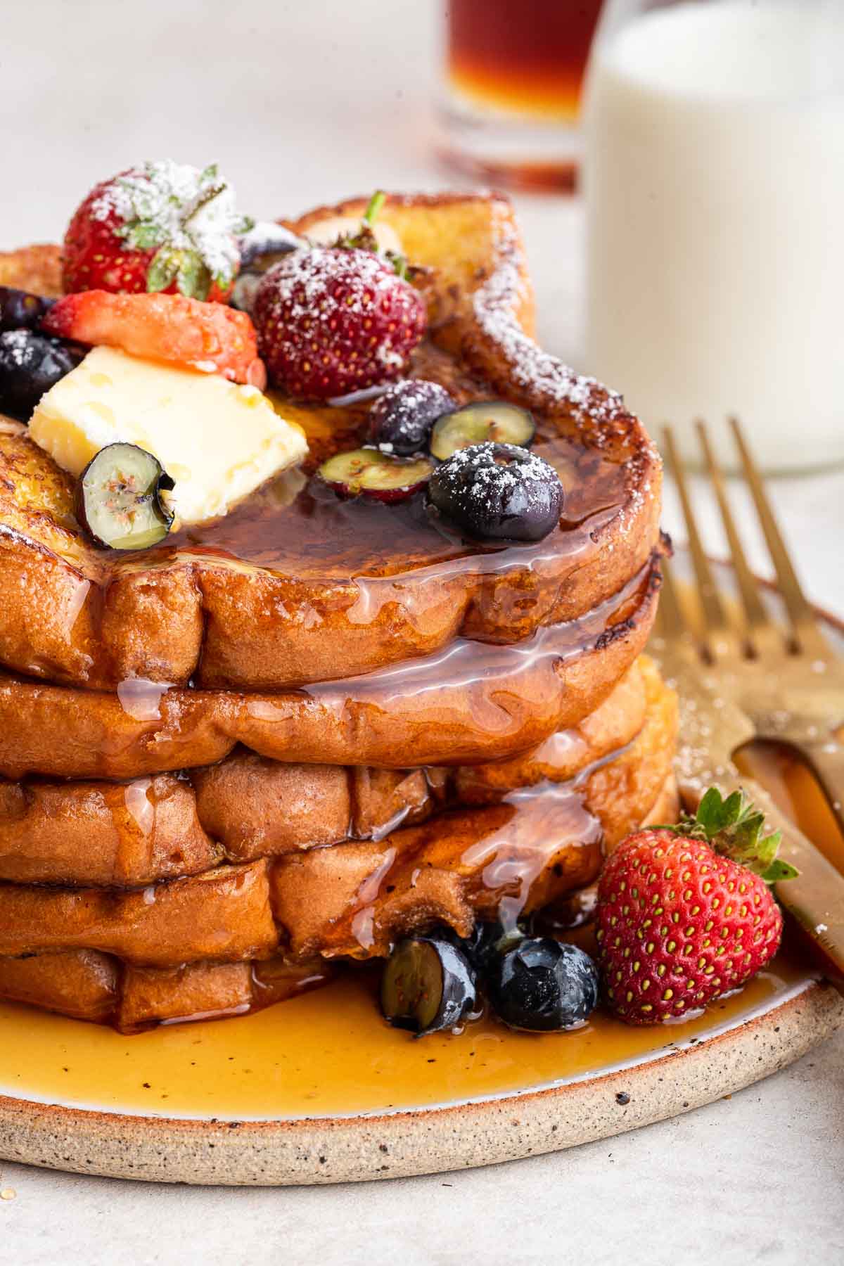 french-toast-for-one-or-two Macro shot of stacked bread slices covered in maple syrup, berries and butter slices.