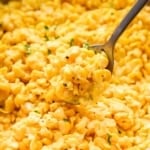 Upclose image of buttered corn in a skillet with a spoon.