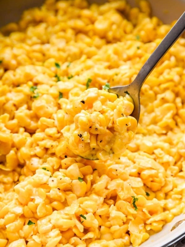 Upclose image of buttered corn in a skillet with a spoon.