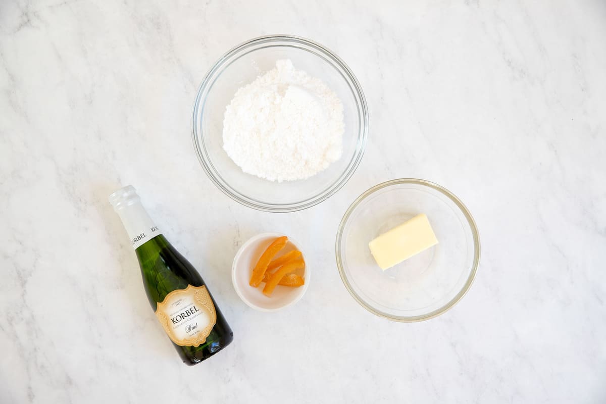 Ingredients for champagne buttercream frosting in small bowls.