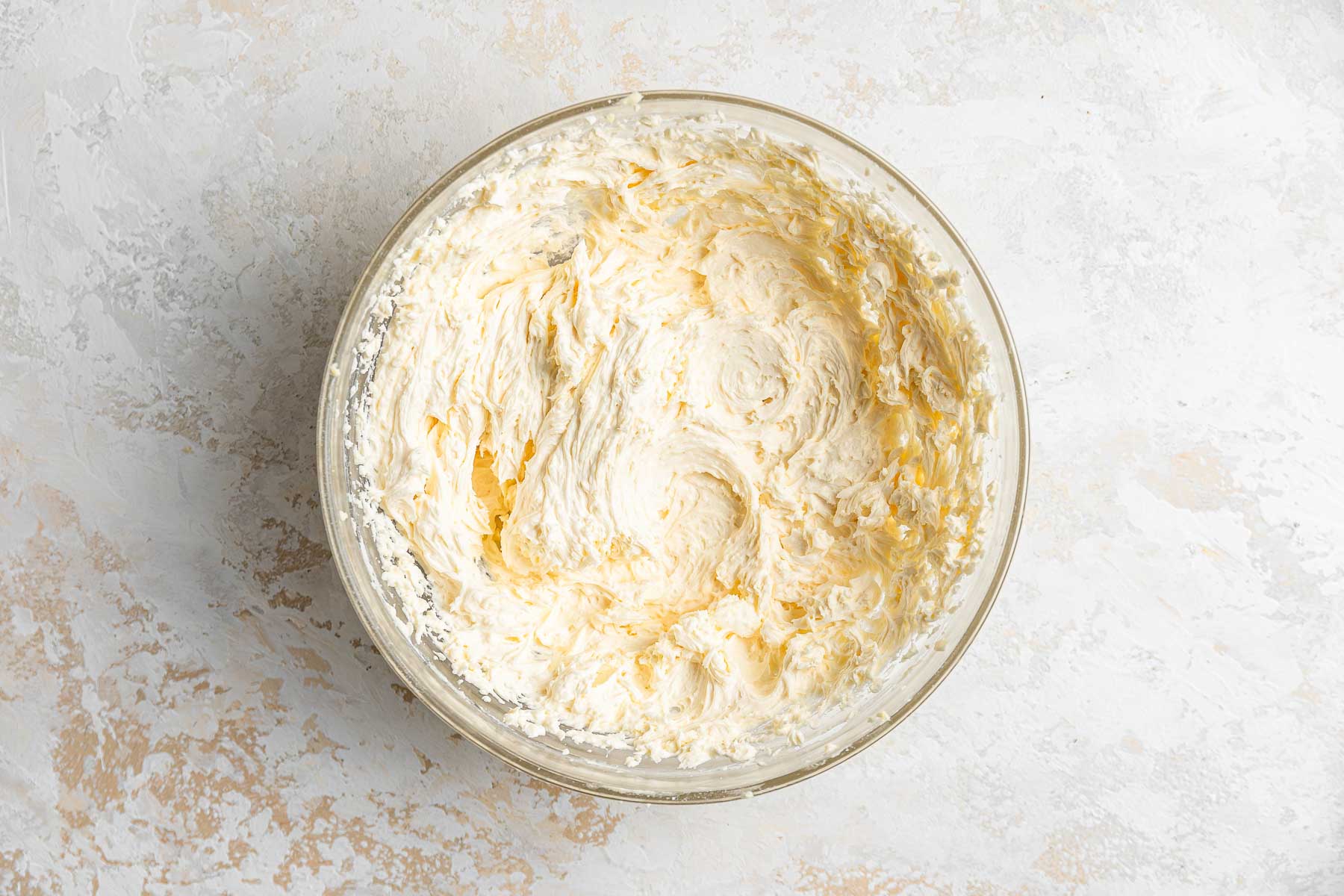 Yellow buttercream frosting in clear glass bowl.