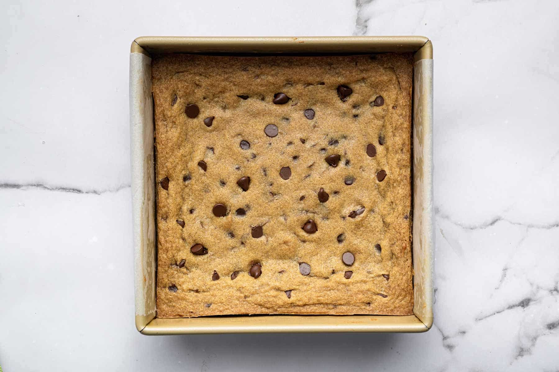 Freshly baked chocolate chip cookie bars in a square baking dish.