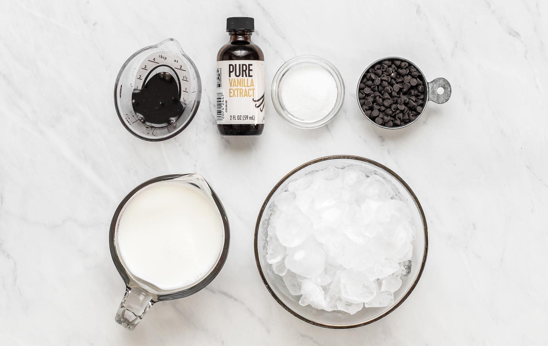 Ingredients to make a chocolate chip frappe on white table.