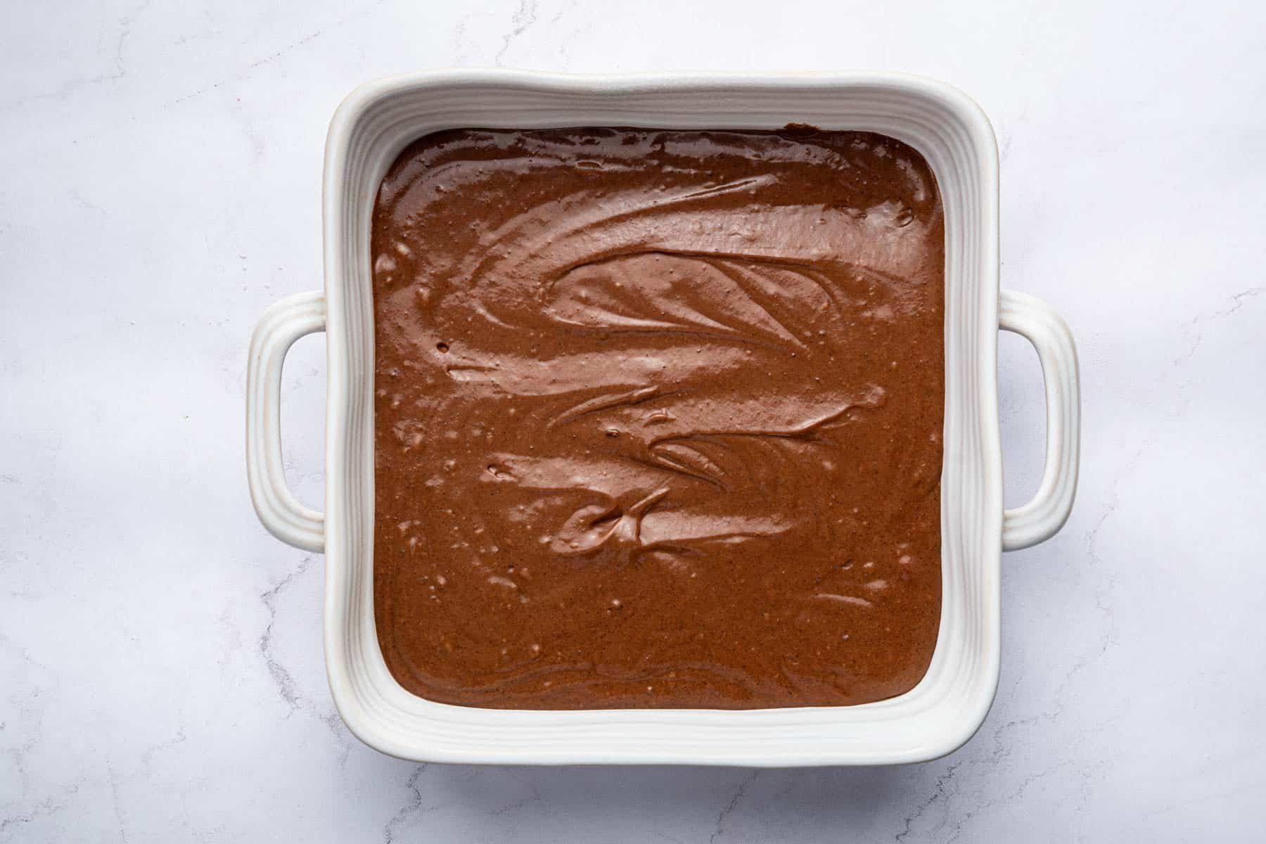 Shiny brown batter spread evenly in an 8-inch square pan.