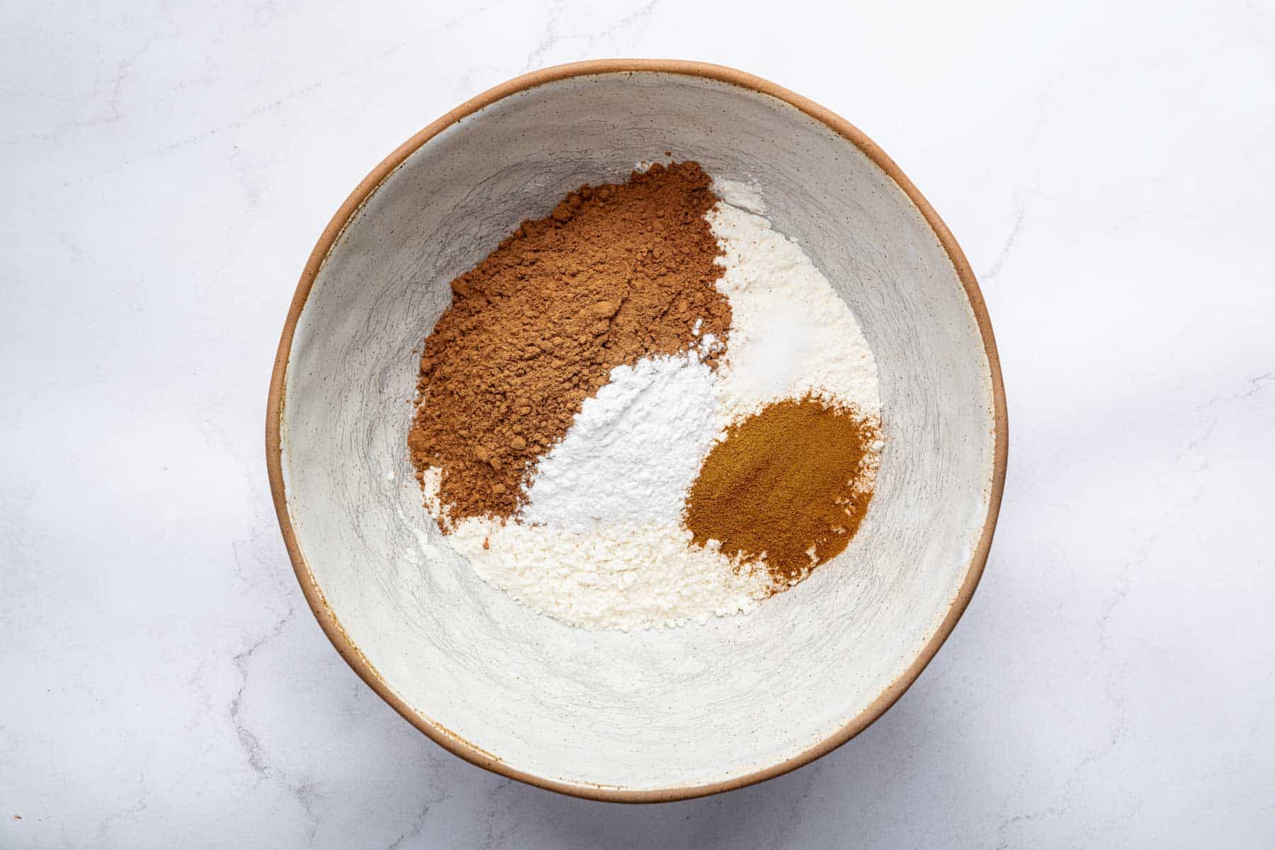 Pottery bowl with cocoa powder, flour, and espresso powder in it.