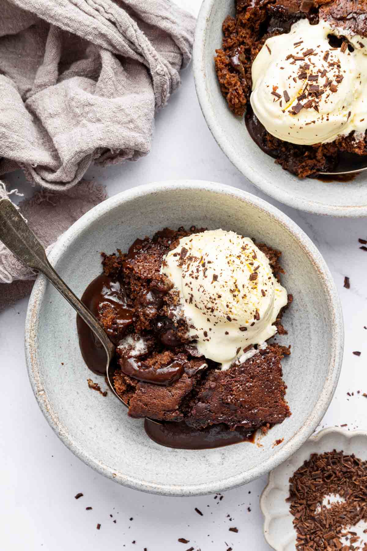 Marco shot of chocolate cobbler in serving bowl with ice cream on top.