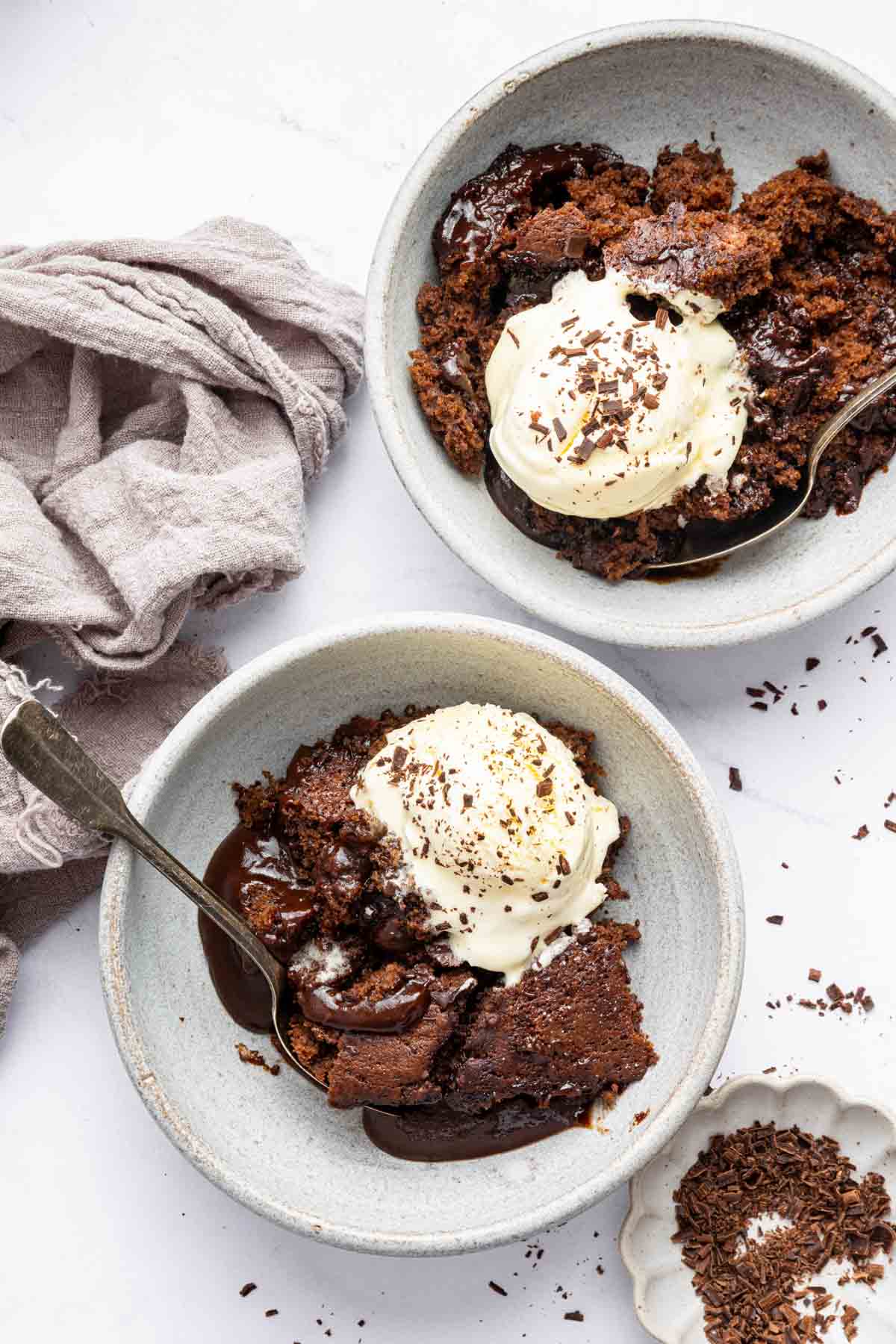 Two bowls of chocolate cobbler topped with vanilla ice cream.