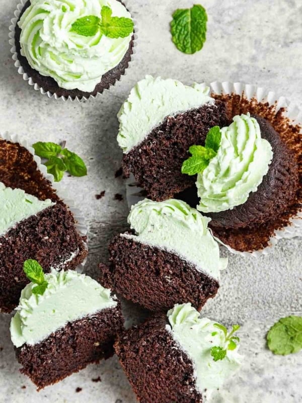 Cut open chocolate mint cupcakes with pale green buttercream.