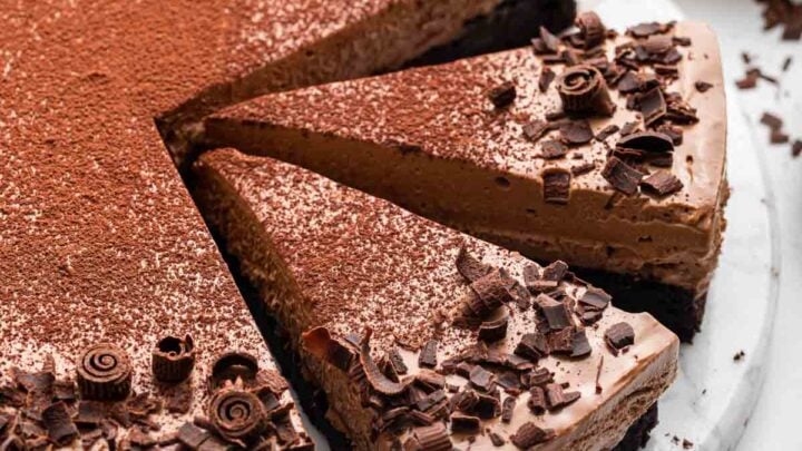 Beautiful sliced chocolate mousse cake on a marble round board.