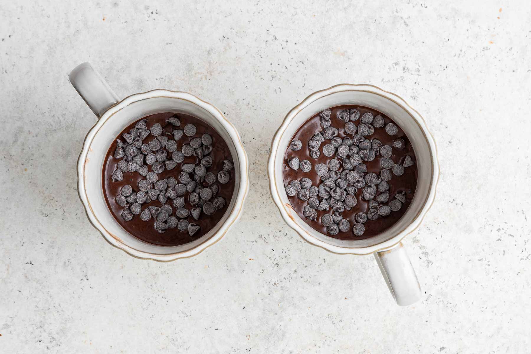 Chocolate chips on top of a chocolate mug cake, before cooking in microwave.