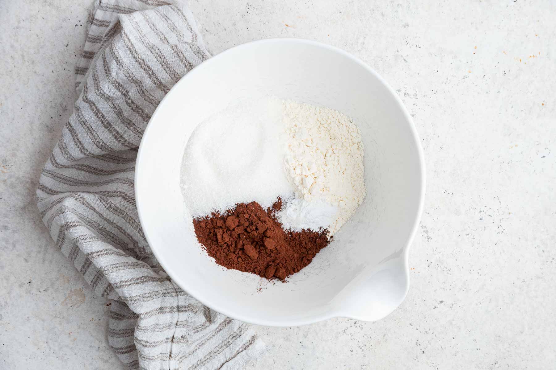 White bowl with flour, cocoa powder, baking powder and salt.
