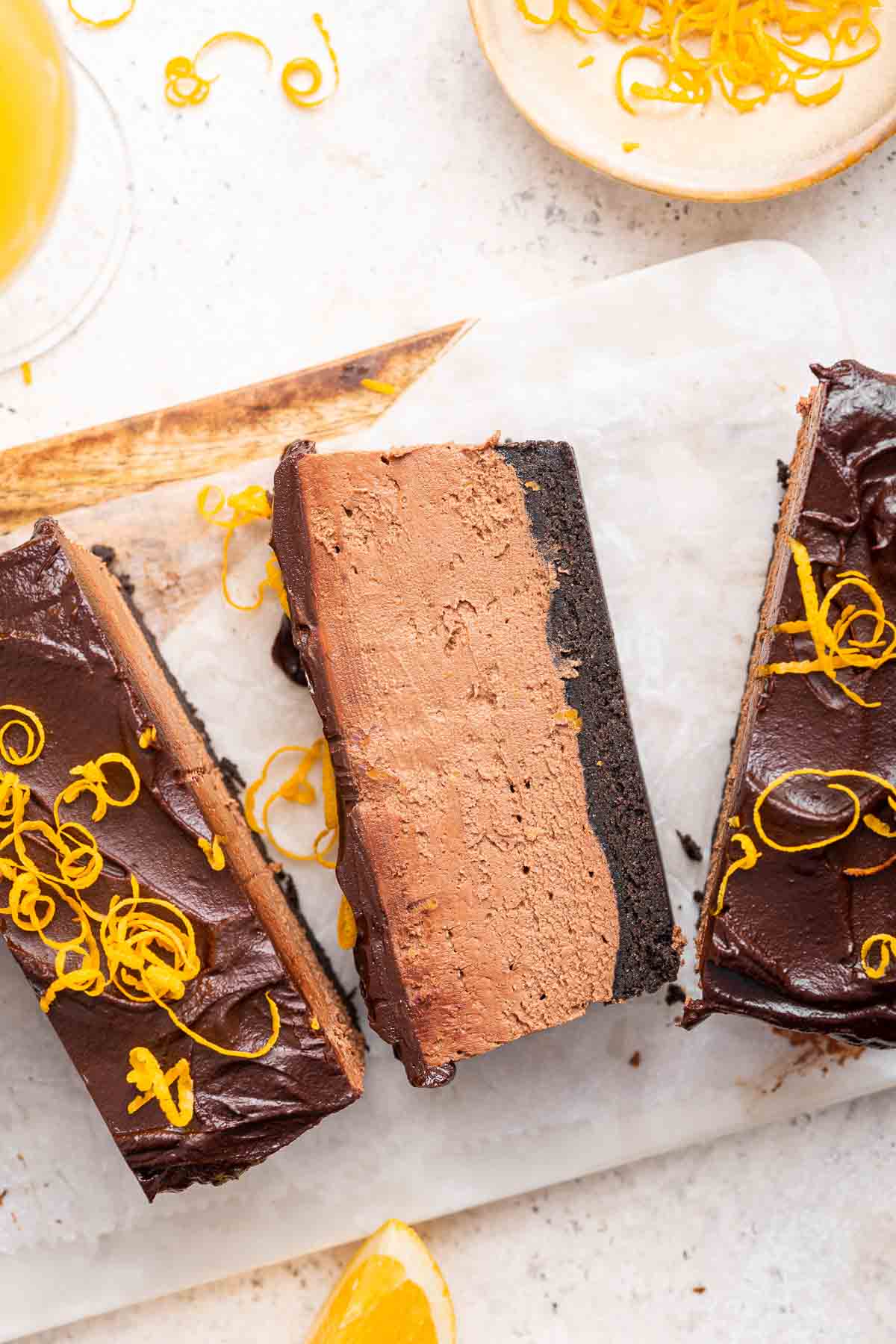 Slices of chocolate orange cheesecake on white cutting board.