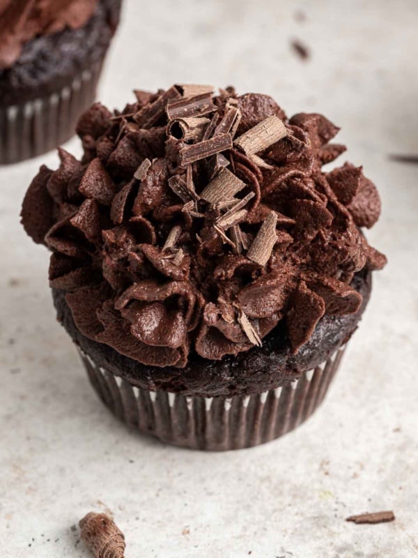 Close up of chocolate cupcake with piped chocolate whipped cream on top.