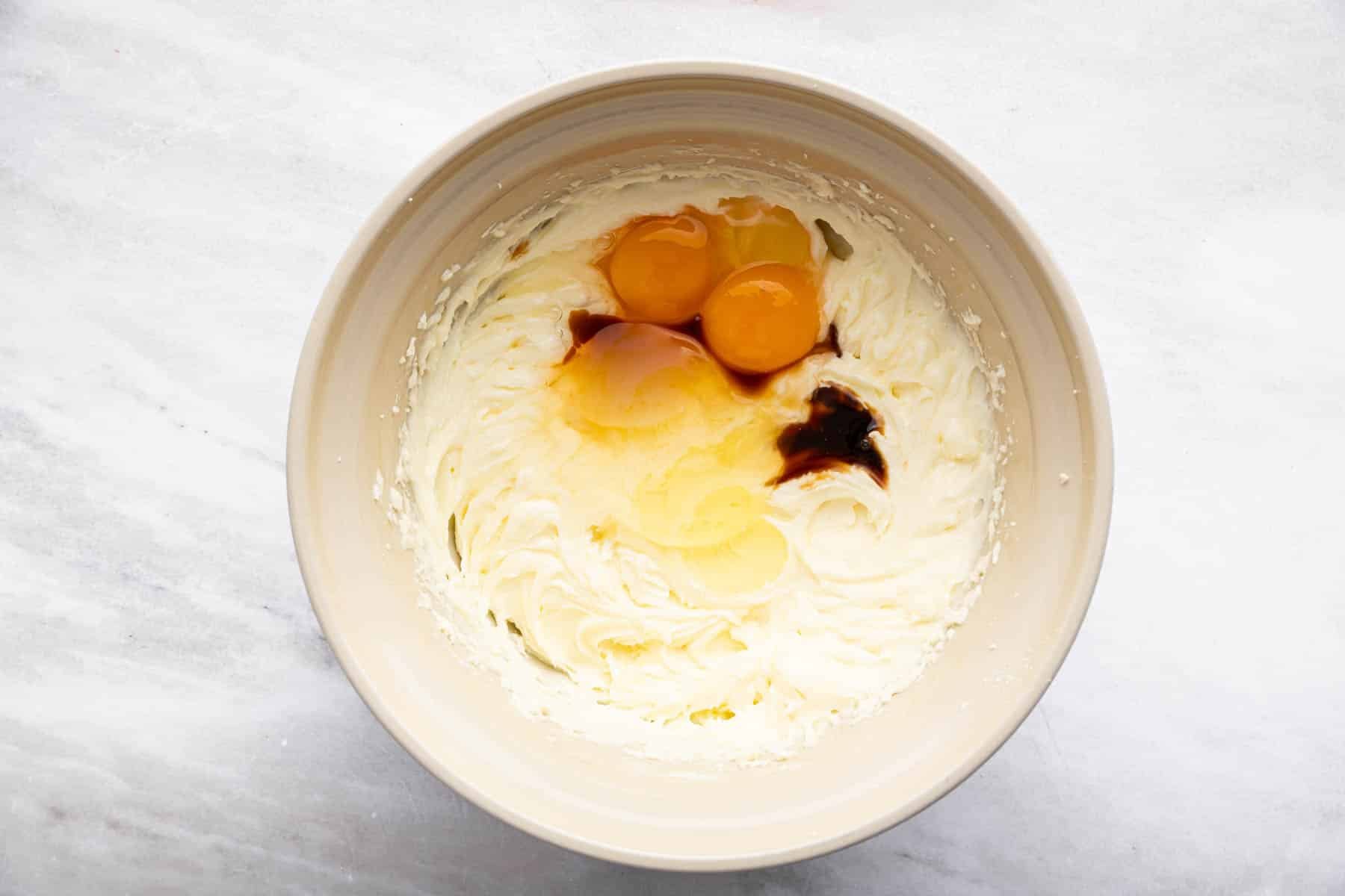 Bowl with two egg yolks and vanilla extract splashed on top.