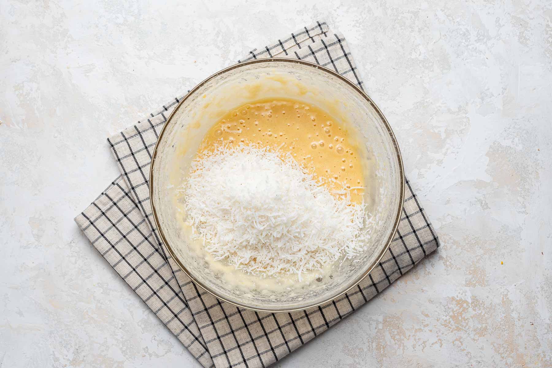Adding coconut flakes to coconut cupcakes batter.