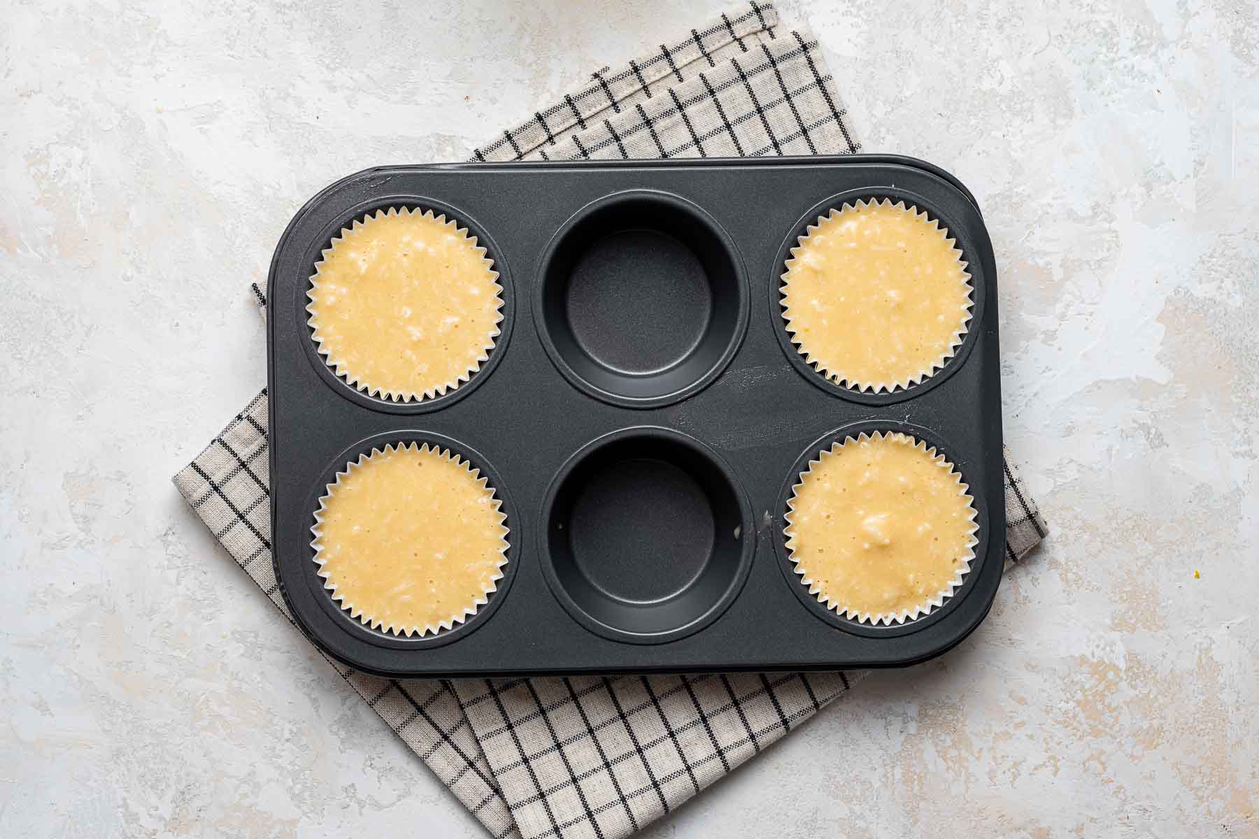 Raw coconut cupcake batter in muffin pan.
