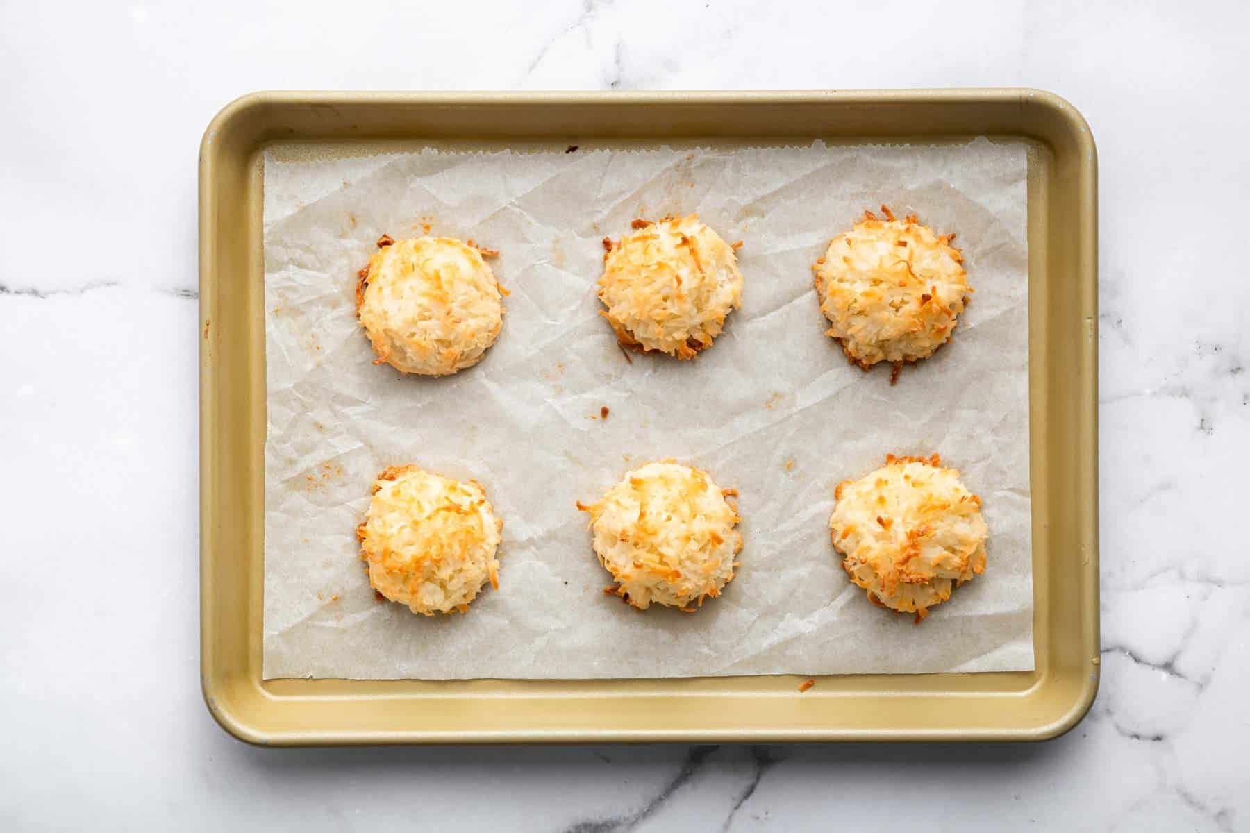 Golden brown coconut macaroons on a baking sheet right out of the oven.