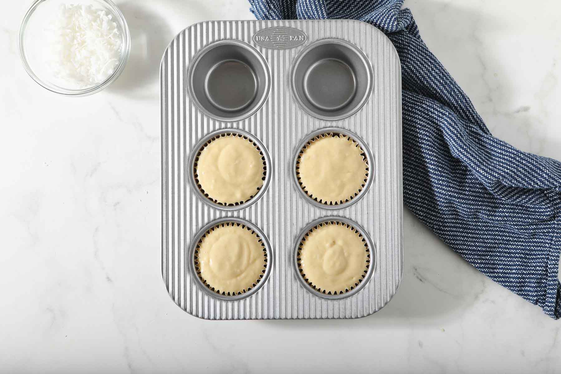 Raw coconut muffin batter in pan.