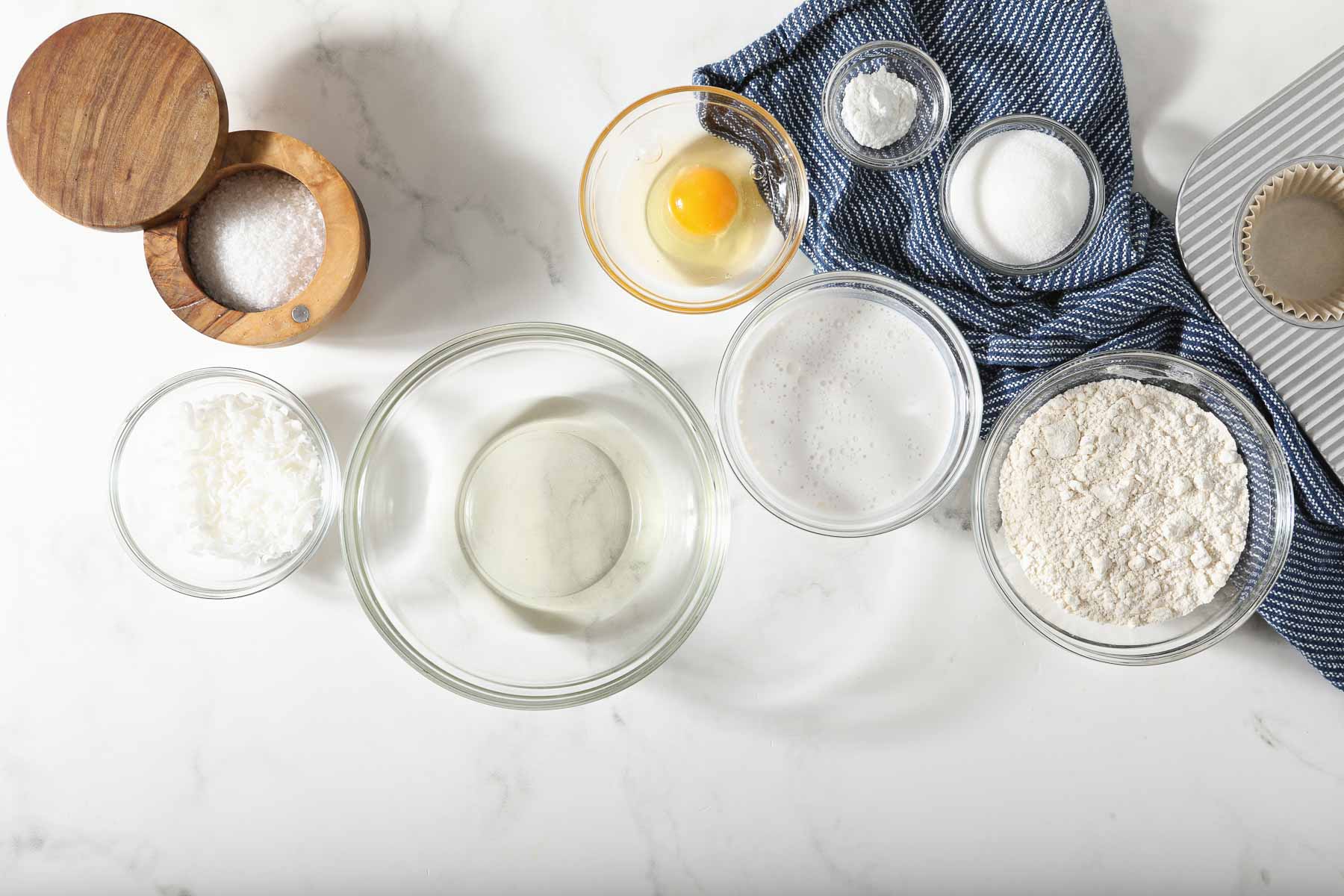 Ingredients for coconut muffins on white table.