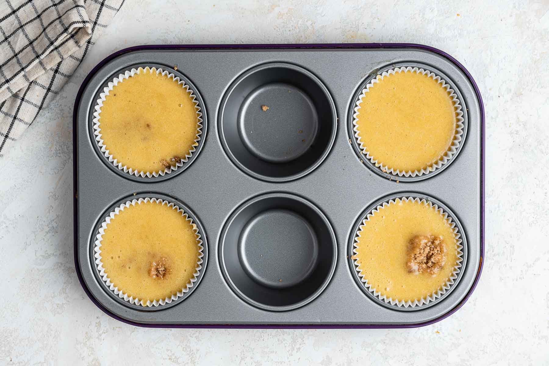 Muffin pan with only 4 cups full of yellow batter.