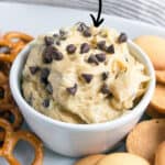 bowl of cookie dough with mini chocolate chips on top and cookies on side.