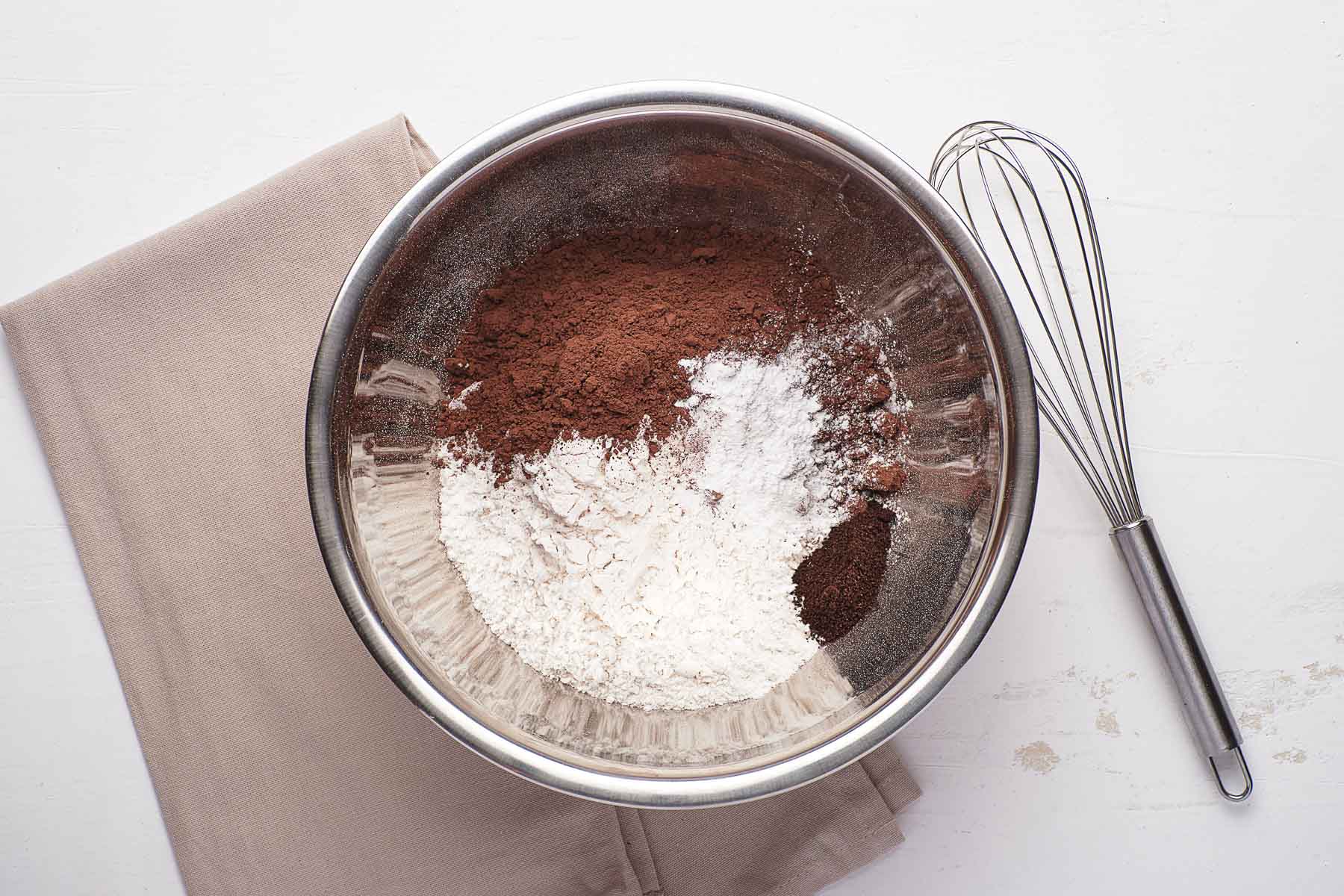 Dry ingredients for baking together in bowl with whisk on side.