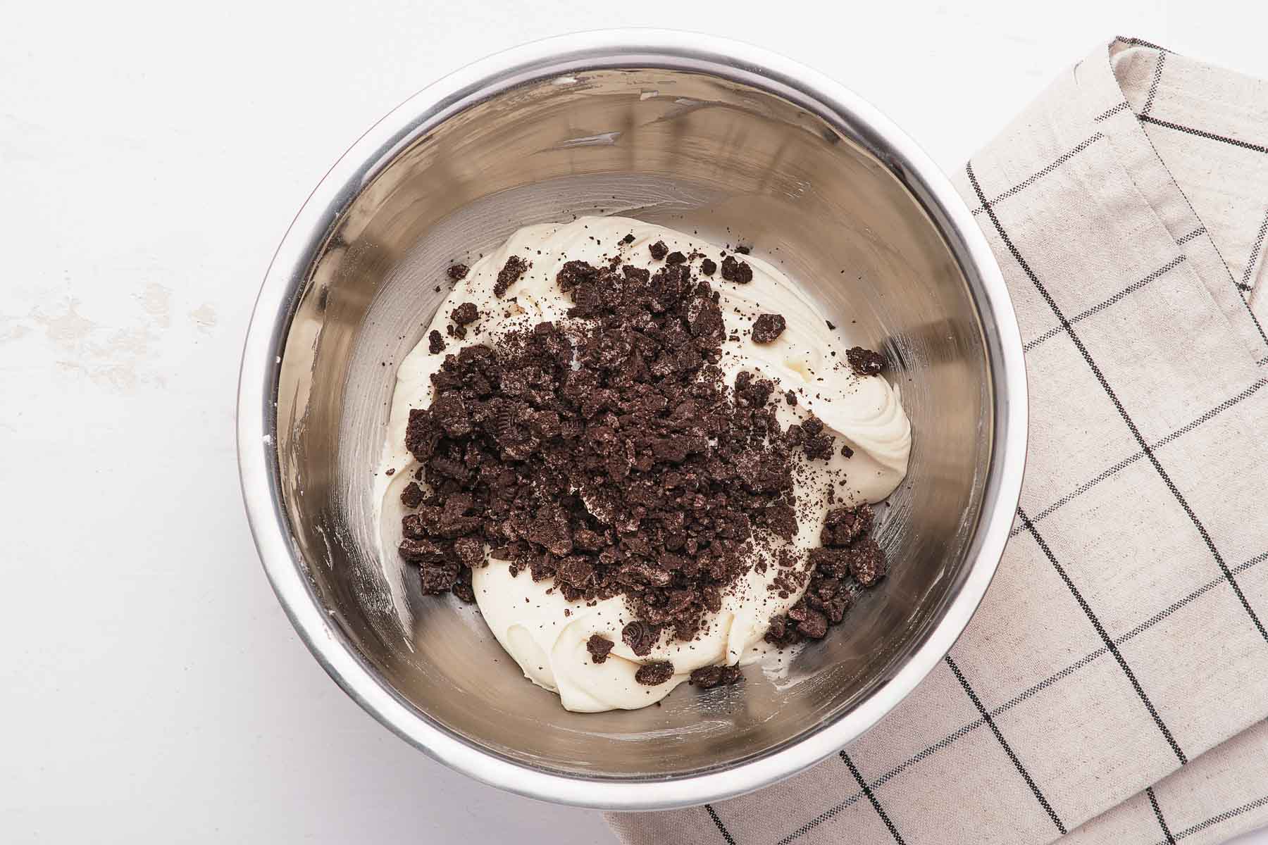 Crushed cookies on top of white frosting in bowl.