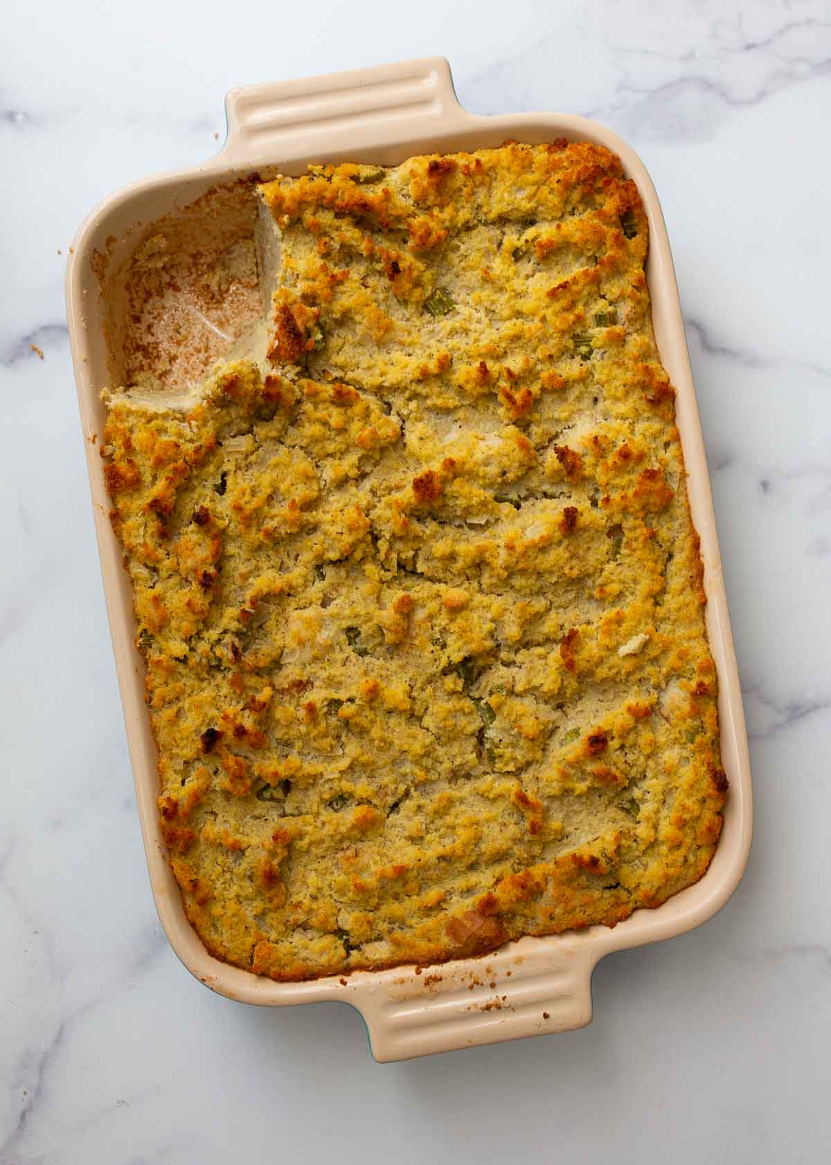 One scoop missing from a pan of southern dressing made with cornbread.