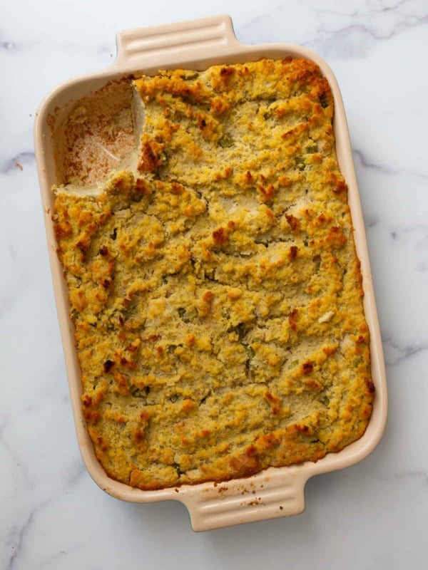 One scoop missing from a pan of southern dressing made with cornbread.