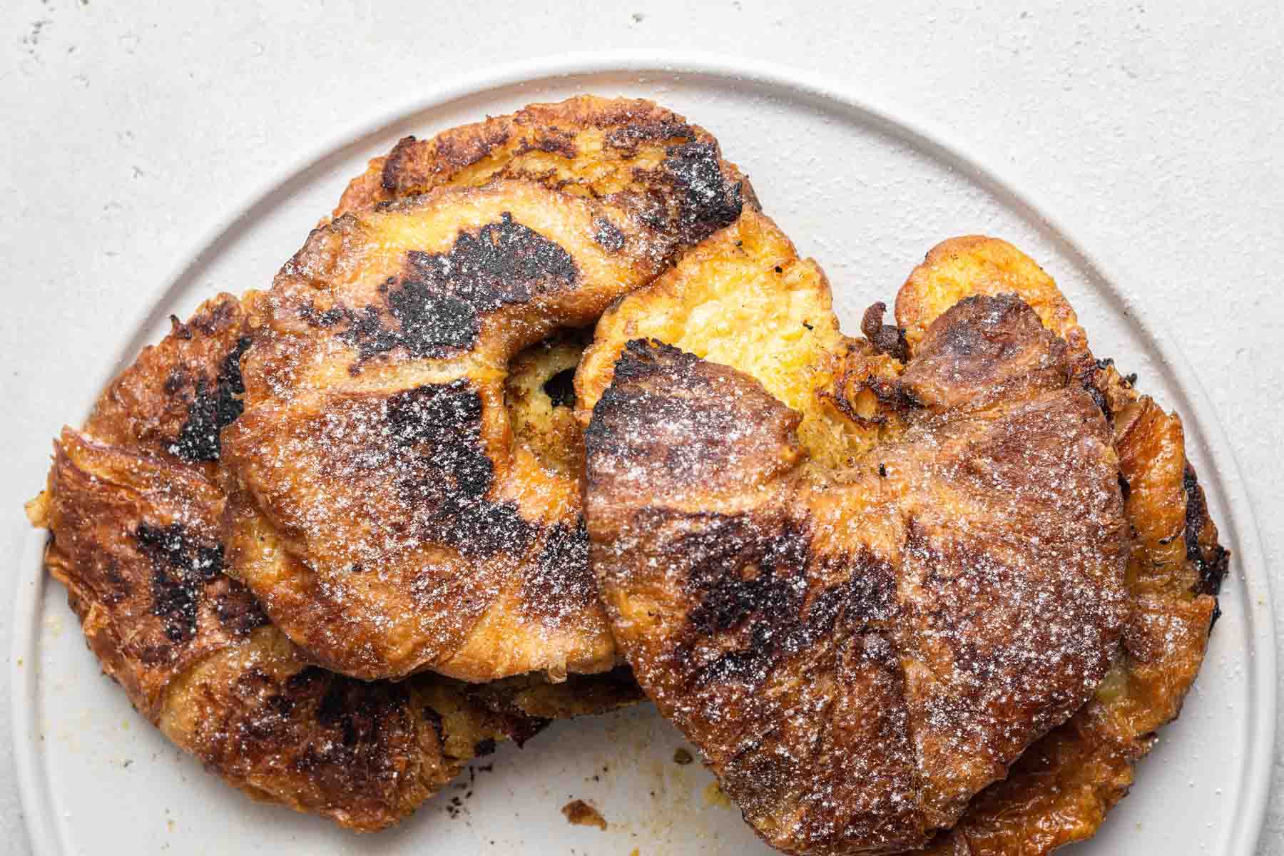 Croissants sprinkled with powdered sugar on plate.