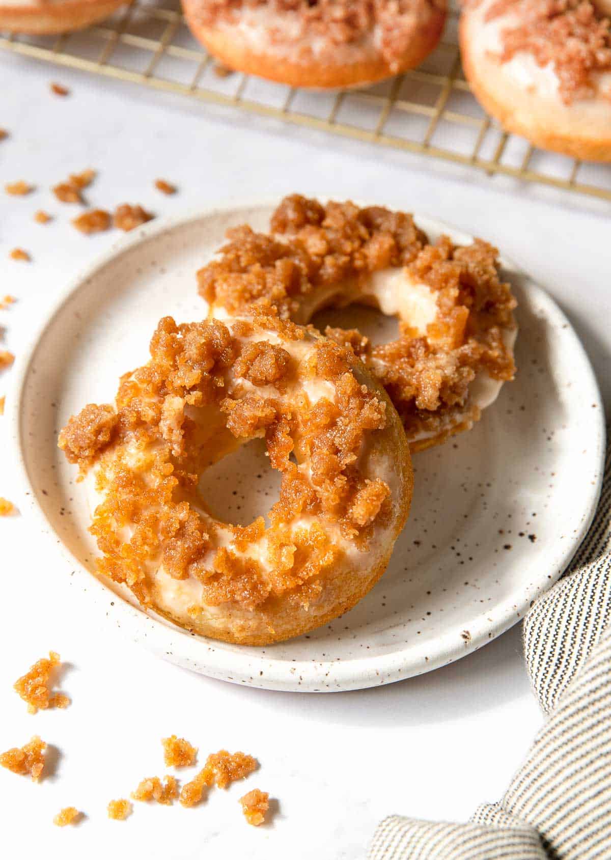 Two streusel topped donuts on a plate.