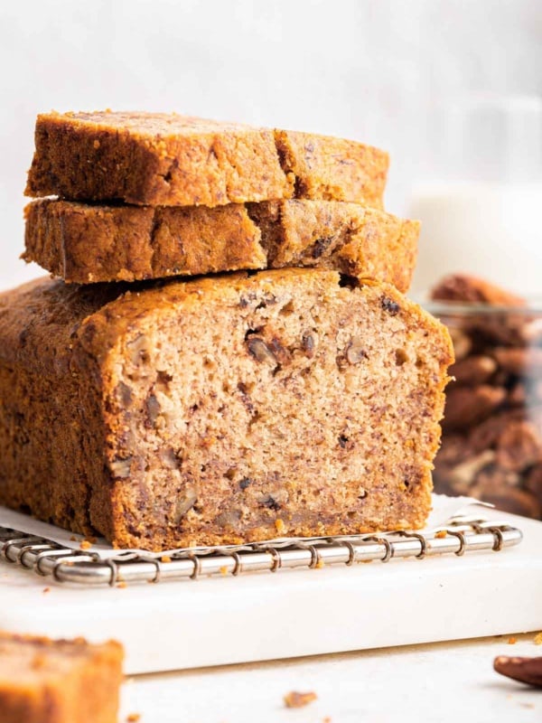 Loaf of eggless banana bread sliced with two slices on top.