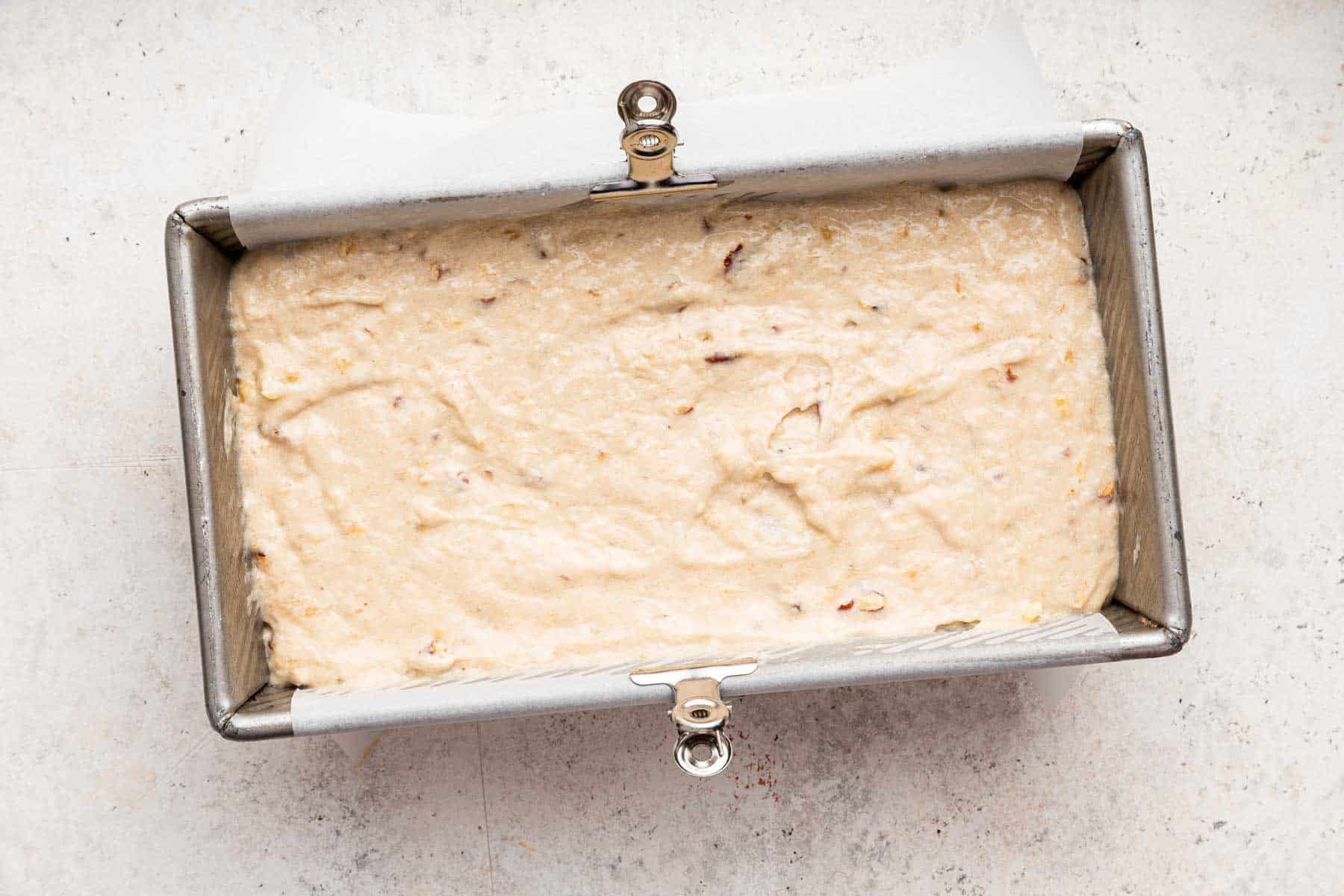 Pale yellow batter in a bread loaf pan.