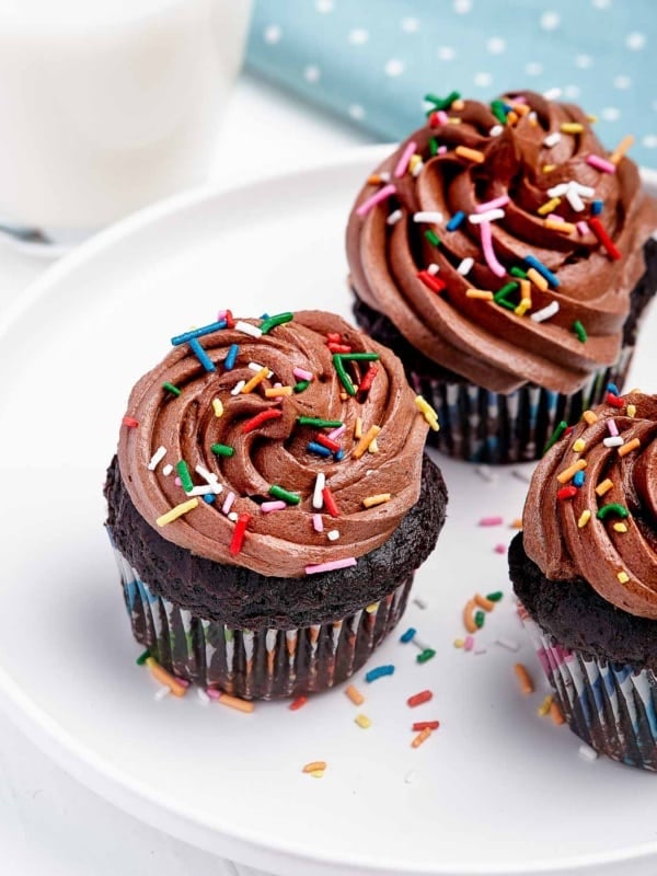 Plate of cupcakes with chocolate frosting and sprinkles.