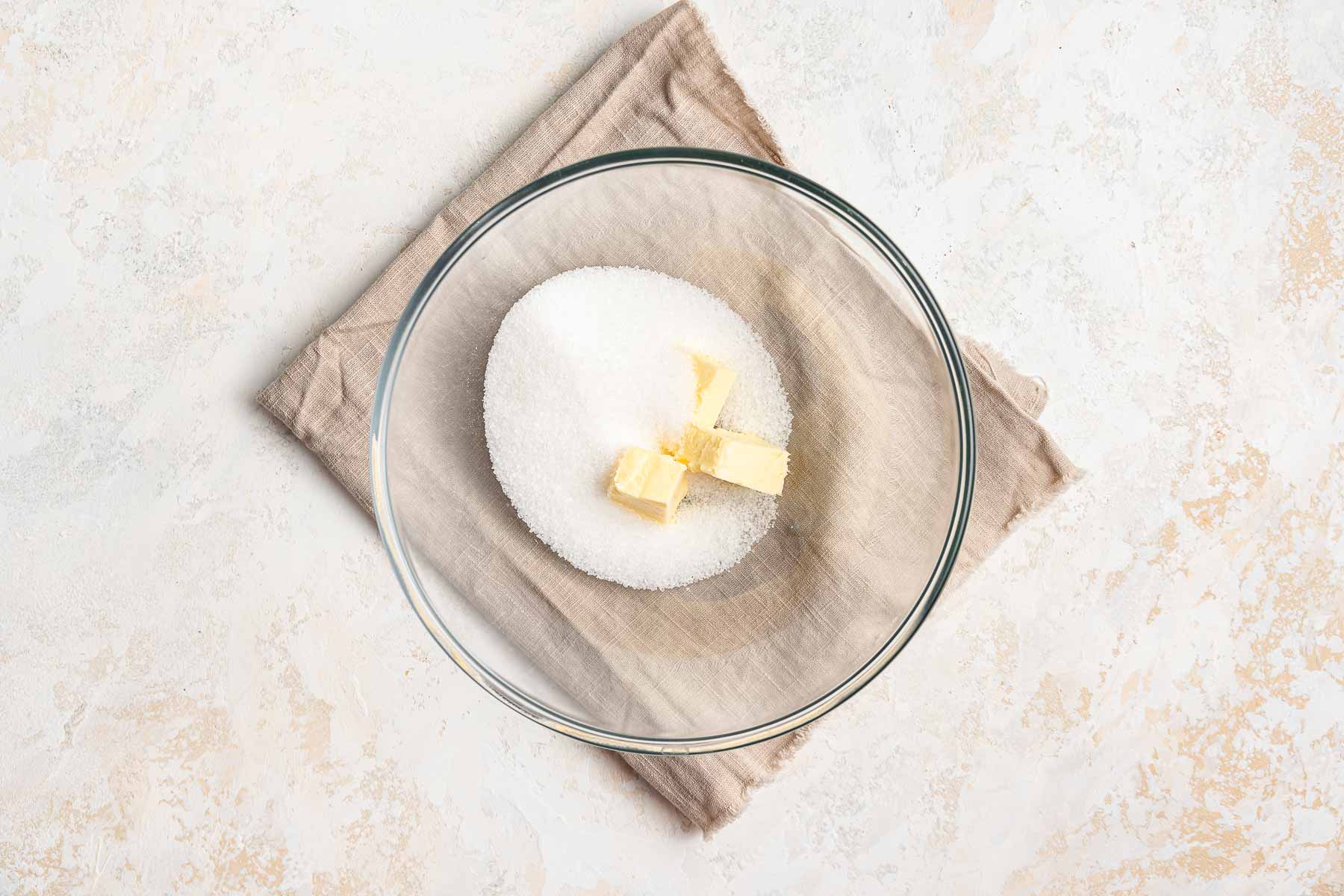 Butter and granulated sugar in clear bowl.