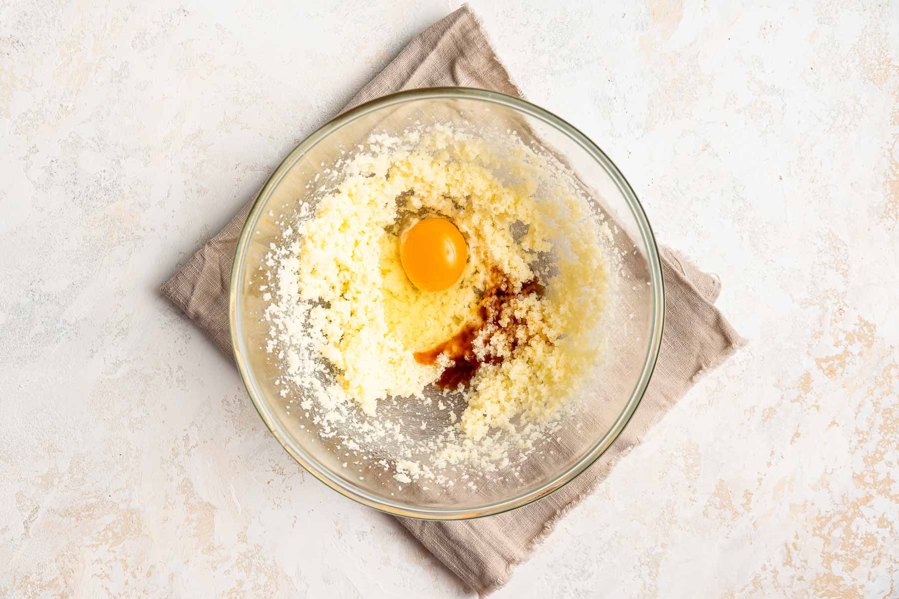 Adding an egg and vanilla to cake batter.