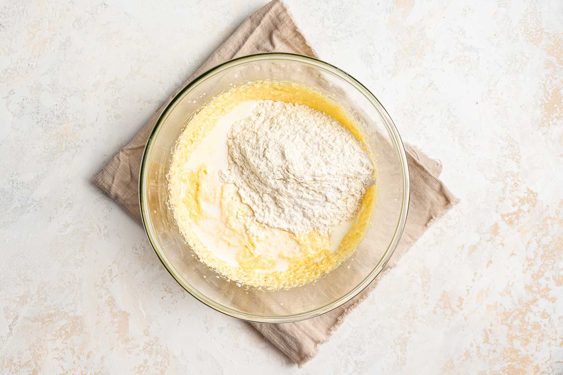 Adding dry ingredients and milk to a cupcake batter in bowl.