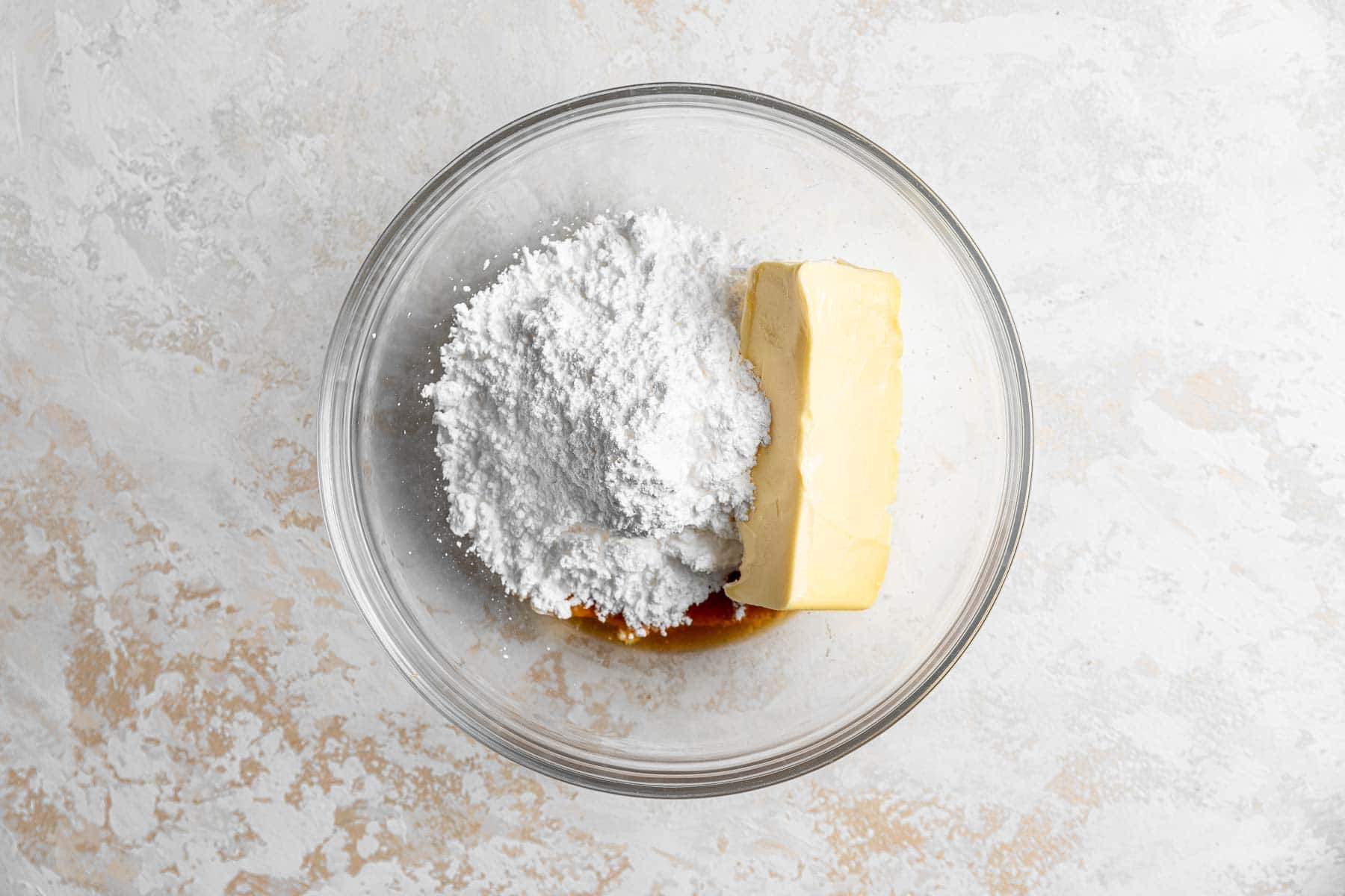 Butter, powdered sugar, and vanilla in clear glass bowl.